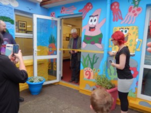 Mr Eamonn Barrett cuts the yellow ribbon to officially open the mural at Piercestown NS